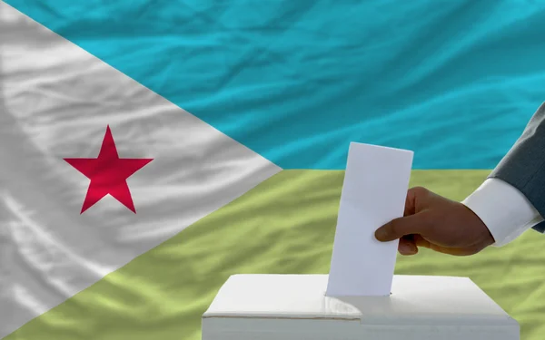 Homme votant sur les élections devant le drapeau national de djibuti — Photo
