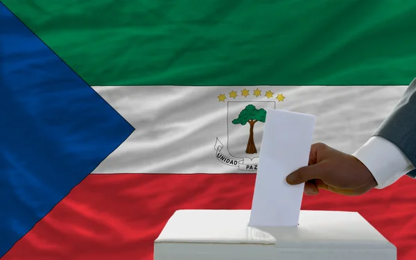 Man voting on elections in front of national flag of equatorial — Zdjęcie stockowe