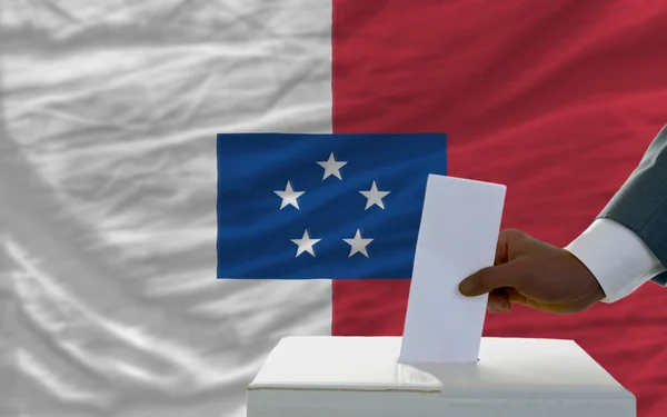 Hombre votando en las elecciones frente a la bandera nacional de franceville —  Fotos de Stock