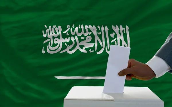 Uomo che vota sulle elezioni davanti alla bandiera nazionale dei sauditi arabi — Foto Stock