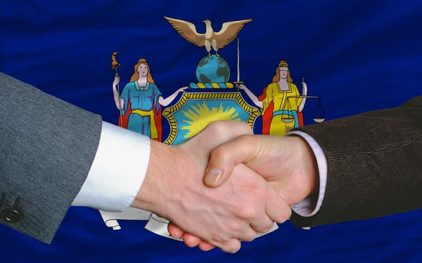 Vor der amerikanischen Staatsflagge von New York Hand in Hand mit zwei Geschäftsleuten — Stockfoto