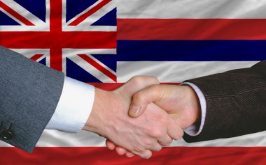 In front of american state flag of hawaii two businessmen handsh clipart