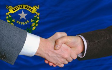 In front of american state flag of nevada two businessmen handsh clipart