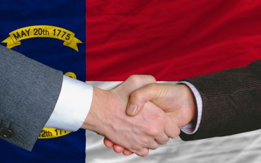 In front of american state flag of north carolina two businessme clipart