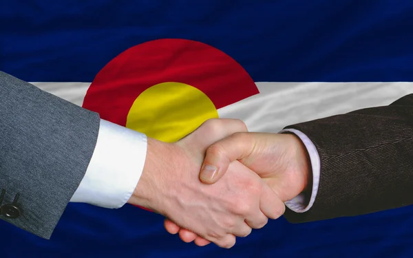 Frente a la bandera del estado americano de Colorado dos hombres de negocios de la mano — Foto de Stock