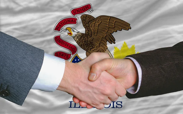 Перед американским флагом штата Иллинойс два бизнесмена протянули руку — стоковое фото