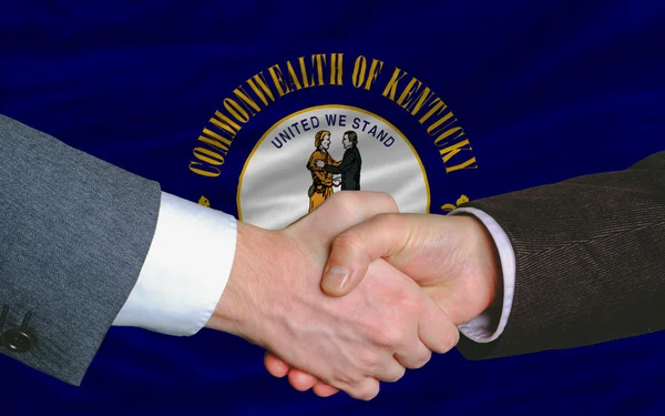 Vor der amerikanischen Staatsflagge von kentucky zwei Geschäftsleute Hand in Hand — Stockfoto