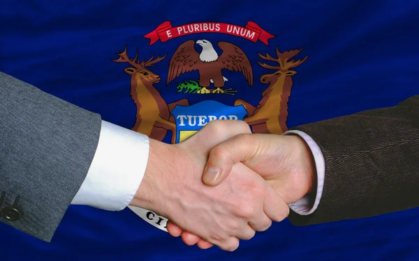 Vor der Flagge des amerikanischen Bundesstaates Michigan zwei Geschäftsleute Hand in Hand — Stockfoto