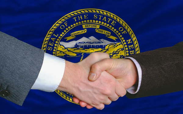 Przed flaga amerykańskiego stanu nebraska dwóch biznesmenów ręki — Zdjęcie stockowe