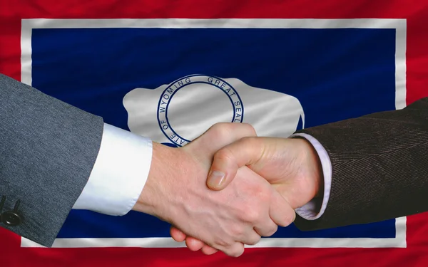 Em frente à bandeira do estado americano de wyoming duas mãos de homens de negócios — Fotografia de Stock