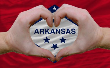 Over american state flag of arkansas showed heart and love gestu clipart