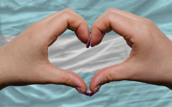 Over national flag of argentina showed heart and love gesture ma — Stock Photo, Image