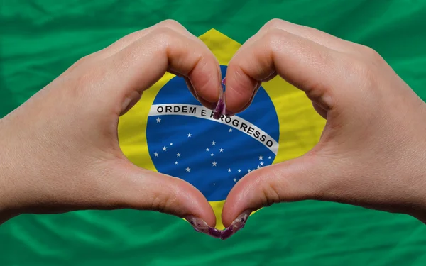 Над национальным флагом Бразилии проявили сердце и любовь жест сделал — стоковое фото