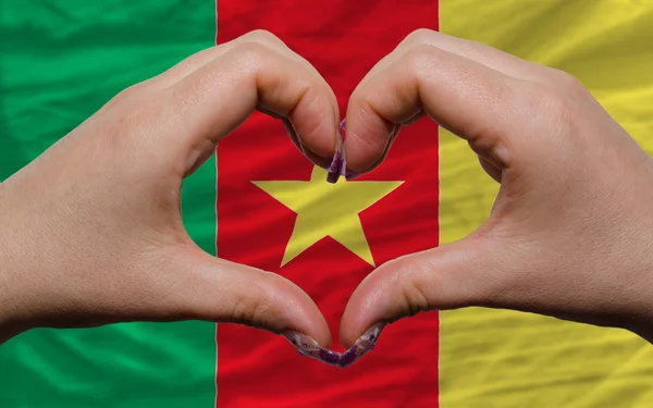 Over national flag of cameroon showed heart and love gesture mad — Stock Photo, Image
