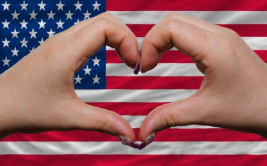 Over national flag of america showed heart and love gesture made clipart