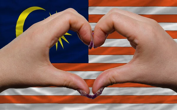 Над национальным флагом Малайзии проявили сердце и любовь жест безумный — стоковое фото