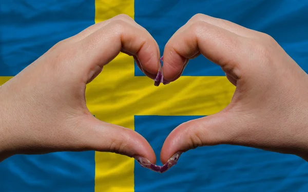 Over national flag of sweden showed heart and love gesture made — Stock Photo, Image