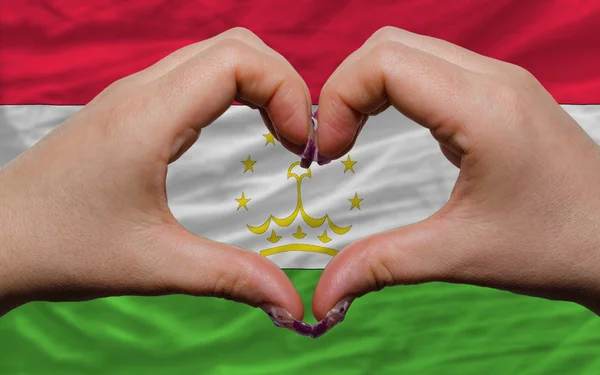 Over national flag of tajikistan showed heart and love gesture m — Stock Photo, Image