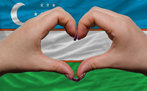 Over national flag of uzbekistan showed heart and love gesture m — Stock Photo, Image