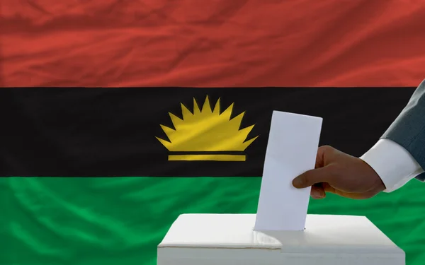 Hombre votando en elecciones frente a bandera nacional de Biafra — Foto de Stock