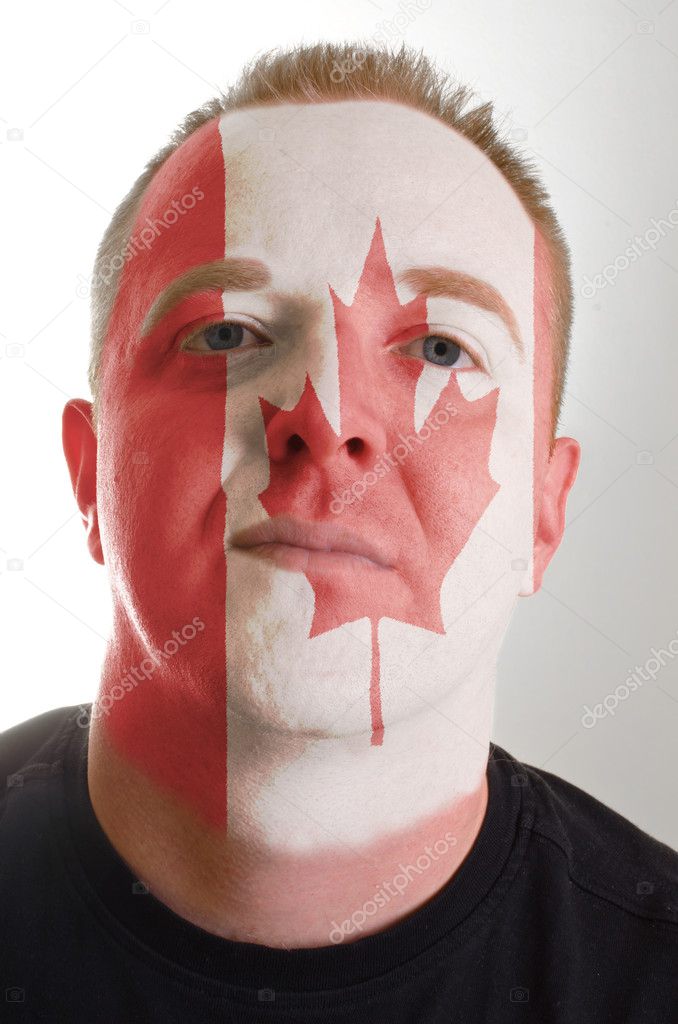 Face of serious patriot man painted in colors of canada flag