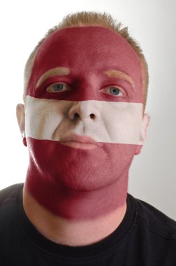 Face of serious patriot man painted in colors of latvia flag clipart