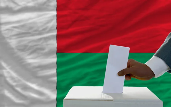Madagaskar bayrağı önünde seçimlerinde oy adam — Stok fotoğraf