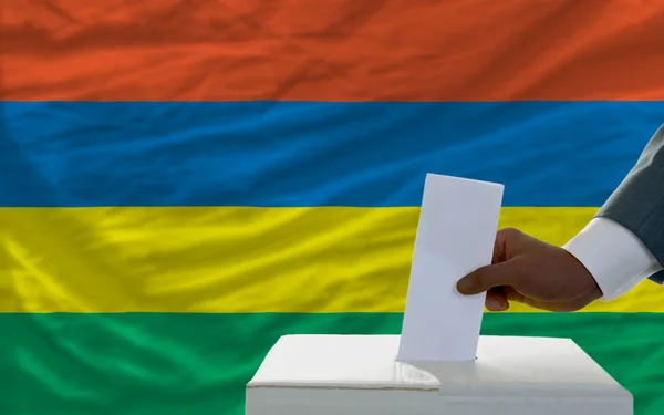 Uomo che vota per le elezioni davanti alla bandiera nazionale di Mauritius — Foto Stock