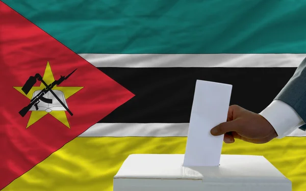 Homem votando nas eleições em frente à bandeira nacional de Moçambique — Fotografia de Stock