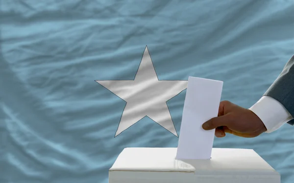 Homme votant sur les élections devant le drapeau national de la Somalie — Photo