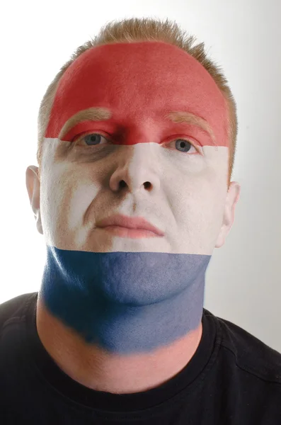 Face of serious patriot man painted in colors of netherlands fla — Stock Photo, Image