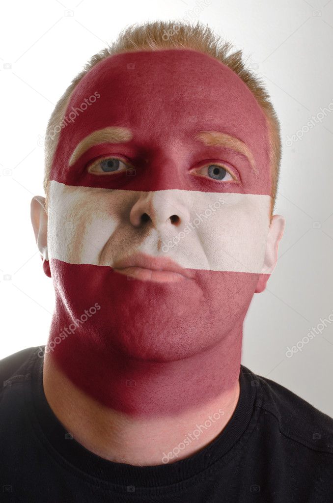 Face of serious patriot man painted in colors of latvia flag