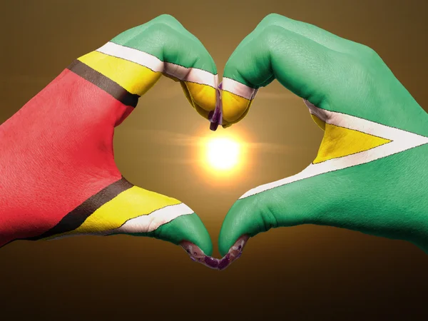 Сердце и любовь жест руками окрашены в флаг Гайаны во время быть — стоковое фото