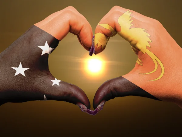 Coração e amor gesto por mãos coloridas em papua nova bandeira da Guiné — Fotografia de Stock