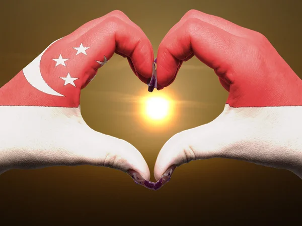 中にシンガポールの国旗の色の心と愛のジェスチャーの手で — ストック写真