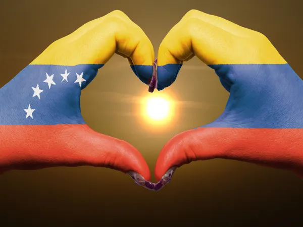 Szív és a szeretet gesztusa, kezében színes, venezuela lobogója alatt — Stock Fotó