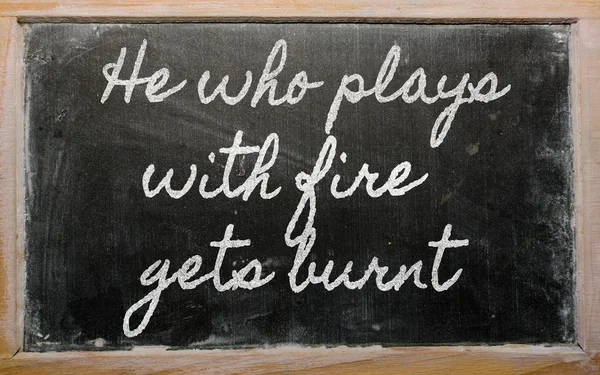 Uttryck - han som spelar med eld blir brända - skriftligt på en s — Stockfoto