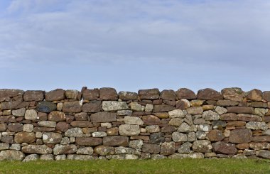 Stone wall in evening light with grass and sky clipart