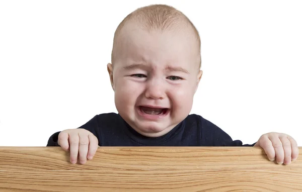 Crying young child holding wooden board — Stock Photo, Image