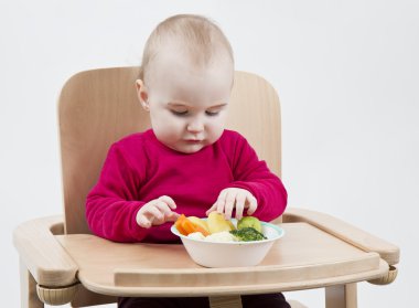 Young child eating in high chair clipart