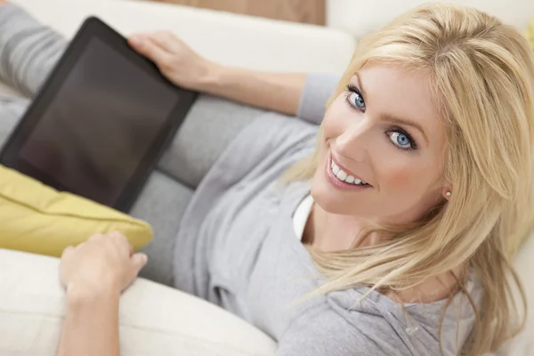 美丽的女人在沙发上使用的平板电脑在家里 — 图库照片