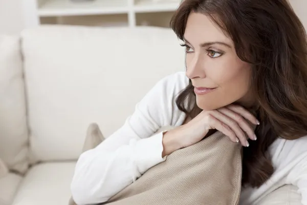 Morena mujer sentada pensando en casa en el sofá —  Fotos de Stock