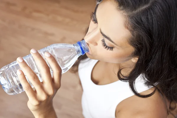 Латиноамериканка-латиноамериканка пьет бутылку воды в спортзале — стоковое фото