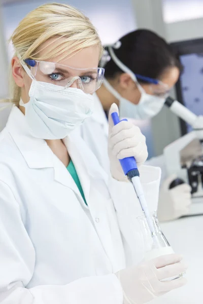Vrouwelijke wetenschapper artsen, Pipetteer & Microscoop in een laboratorium — Stockfoto