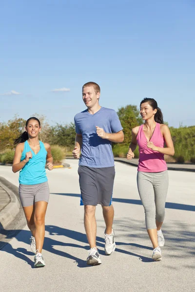 Tres amigos jóvenes adultos interraciales corriendo trotando — Foto de Stock