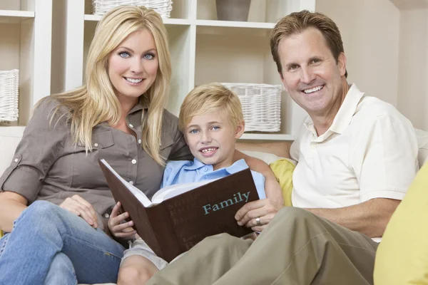 Szczęśliwa rodzina siedzi na kanapie oglądając album fotograficzny — Zdjęcie stockowe
