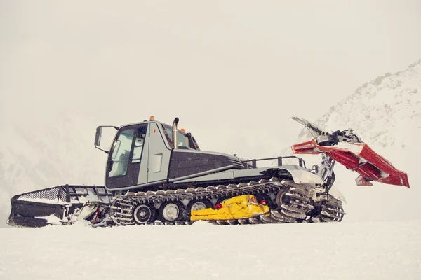 Arado de nieve con un hombre en su cadena de cadenas —  Fotos de Stock