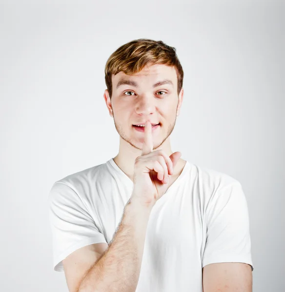 Ung man med fingret över hans mun — Stockfoto