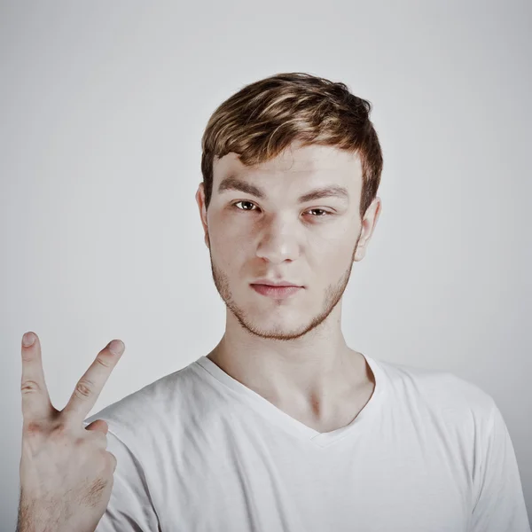 Молодой человек, держащий два пальца — стоковое фото