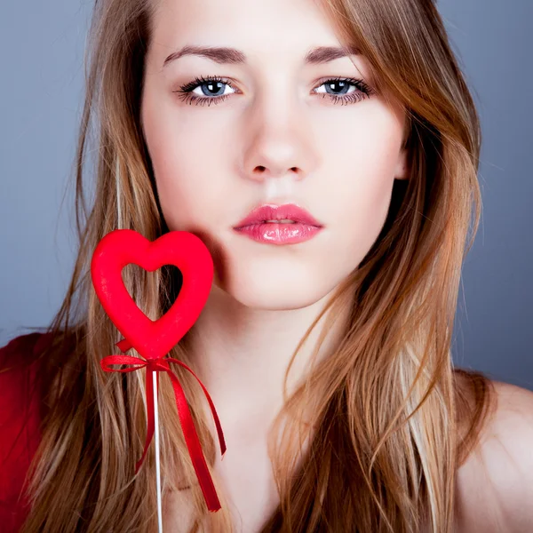 Beautiful young blonde holding a red heart — Stock Photo, Image